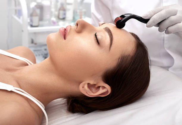 Beautician doing skin treatment using a microneedle dermaroller. Woman having procedure skincare with micro derma facial roller